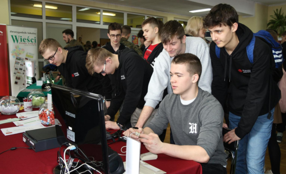 Młodzi mężczyźni grają w retro games na stoisku WSE podczas targów edukacyjnych.