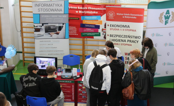 Stoisko Wyższej szkoły Ekonomicznej w Białymstoku. Grupa młodych ludzi zapoznaje się z oferta edukacyjną.